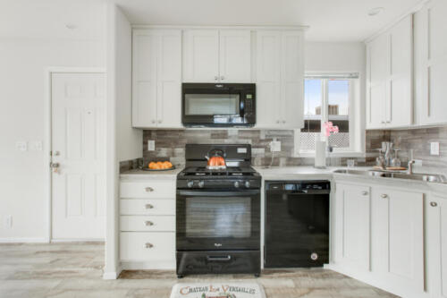 A kitchen with white cabinets and a black stove.